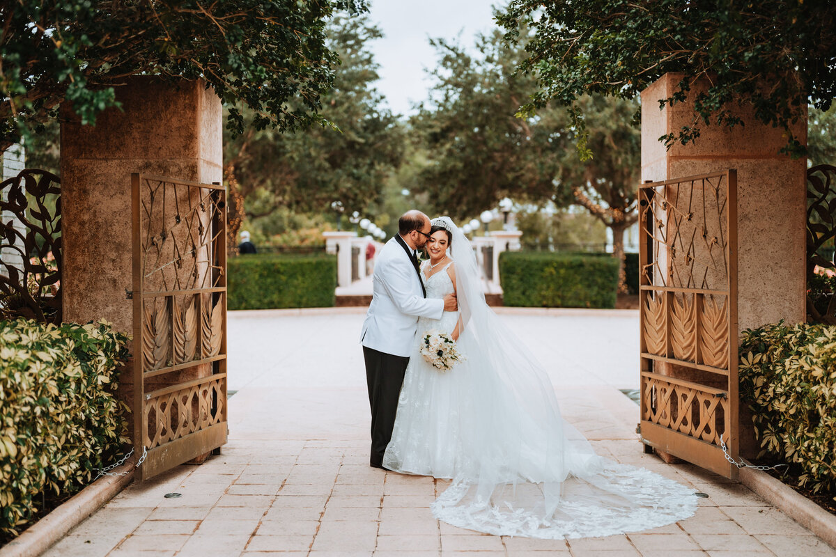 bride and groom standing in between gates at florida botanical gardens Egyptian wedding