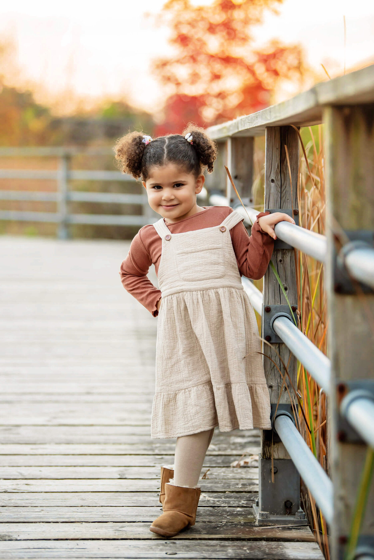 little girl holding a bar on a bridge for her fall family photographer session in Burlington, ON