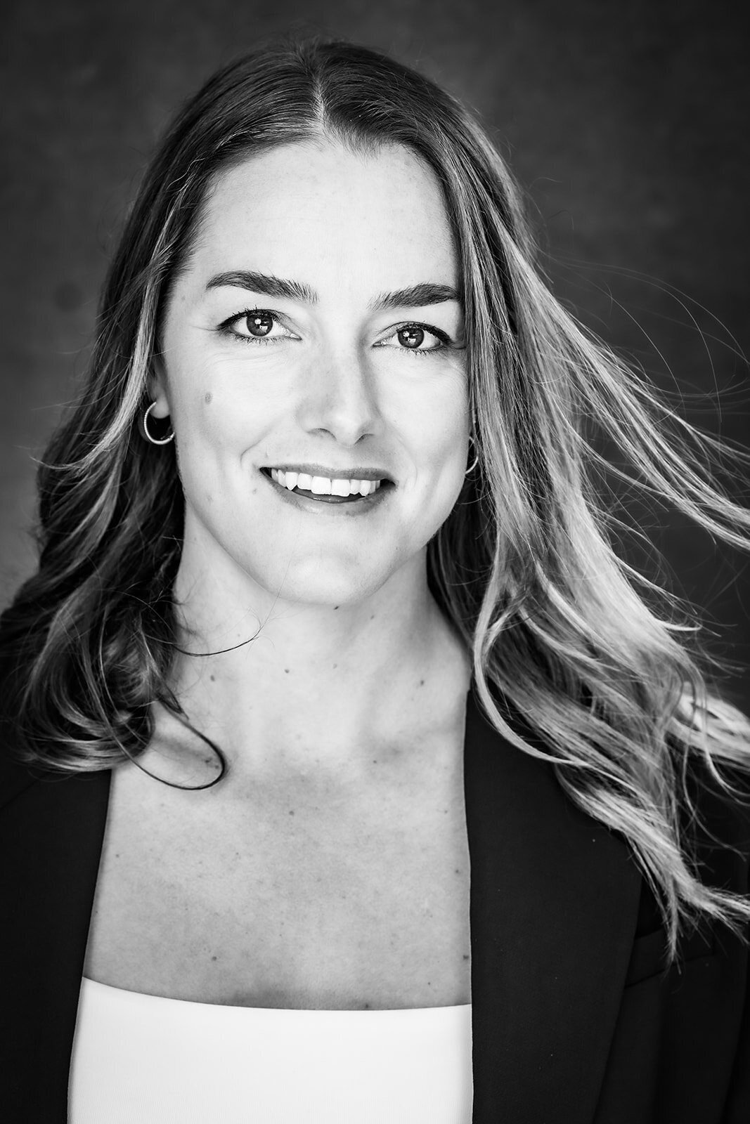 Black and white image of a young woman smiling and her hair blowing in the wind