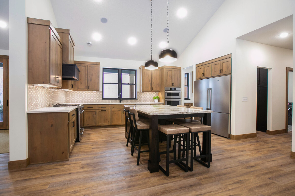 Open kitchen with dark cabinets, large island, and quartz countertops in an Elk River custom home