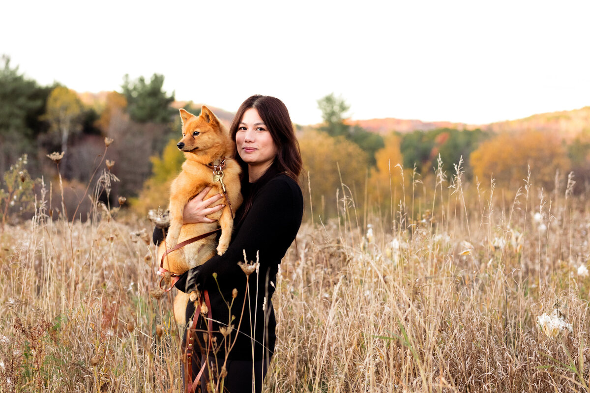 Women holding small dog in a grassy field Vermont Dog Photographer