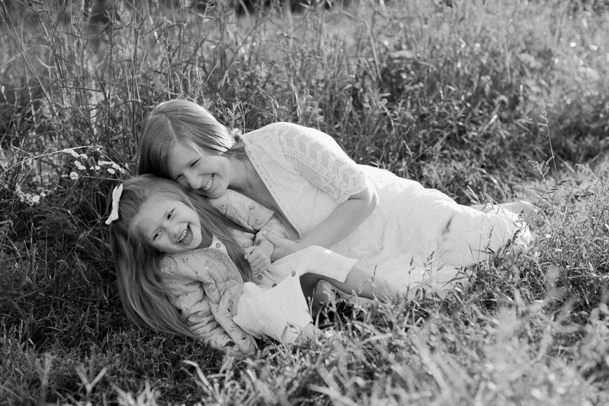 Woman laughs with child as they pose in a flower field.