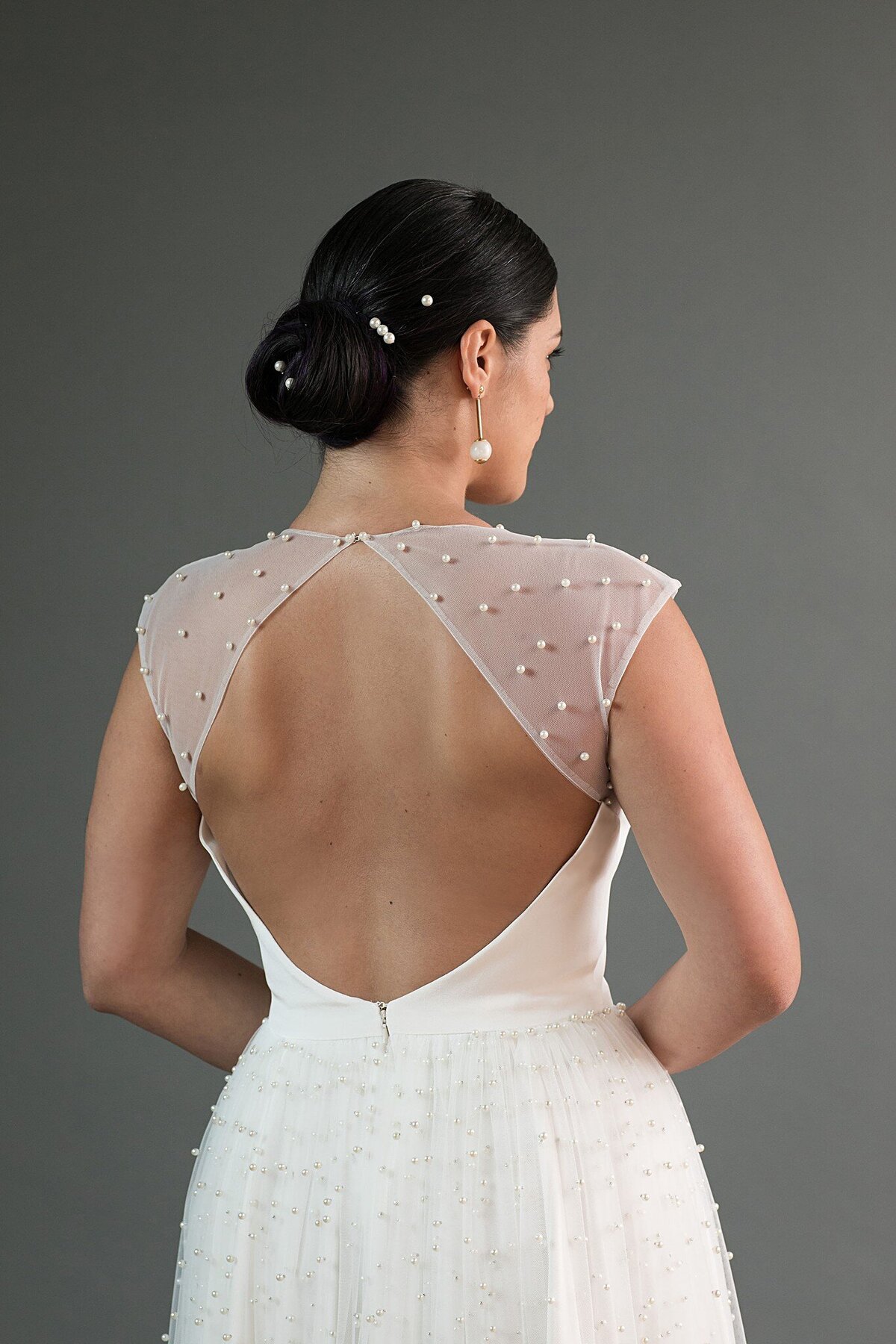 The pearl net of the sheer shoulders closes with a pearl button at the top of the keyhole back.