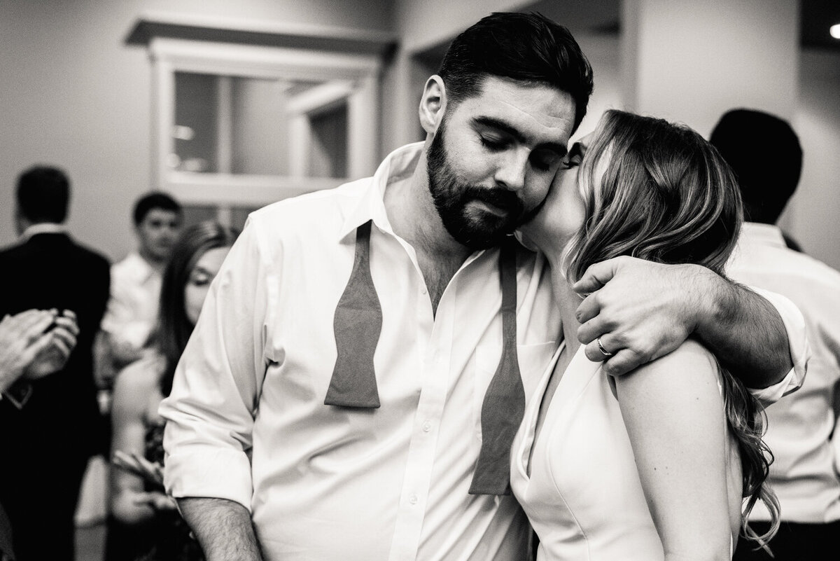 A person kissing their partner on the cheek on their wedding day 