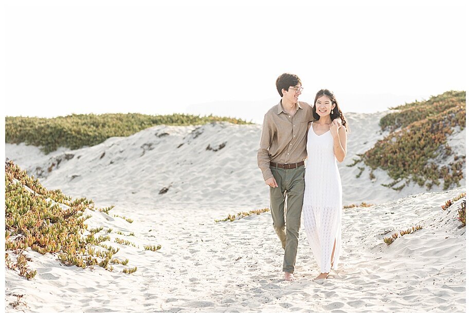 engaged couple walking in sand dunes coronado