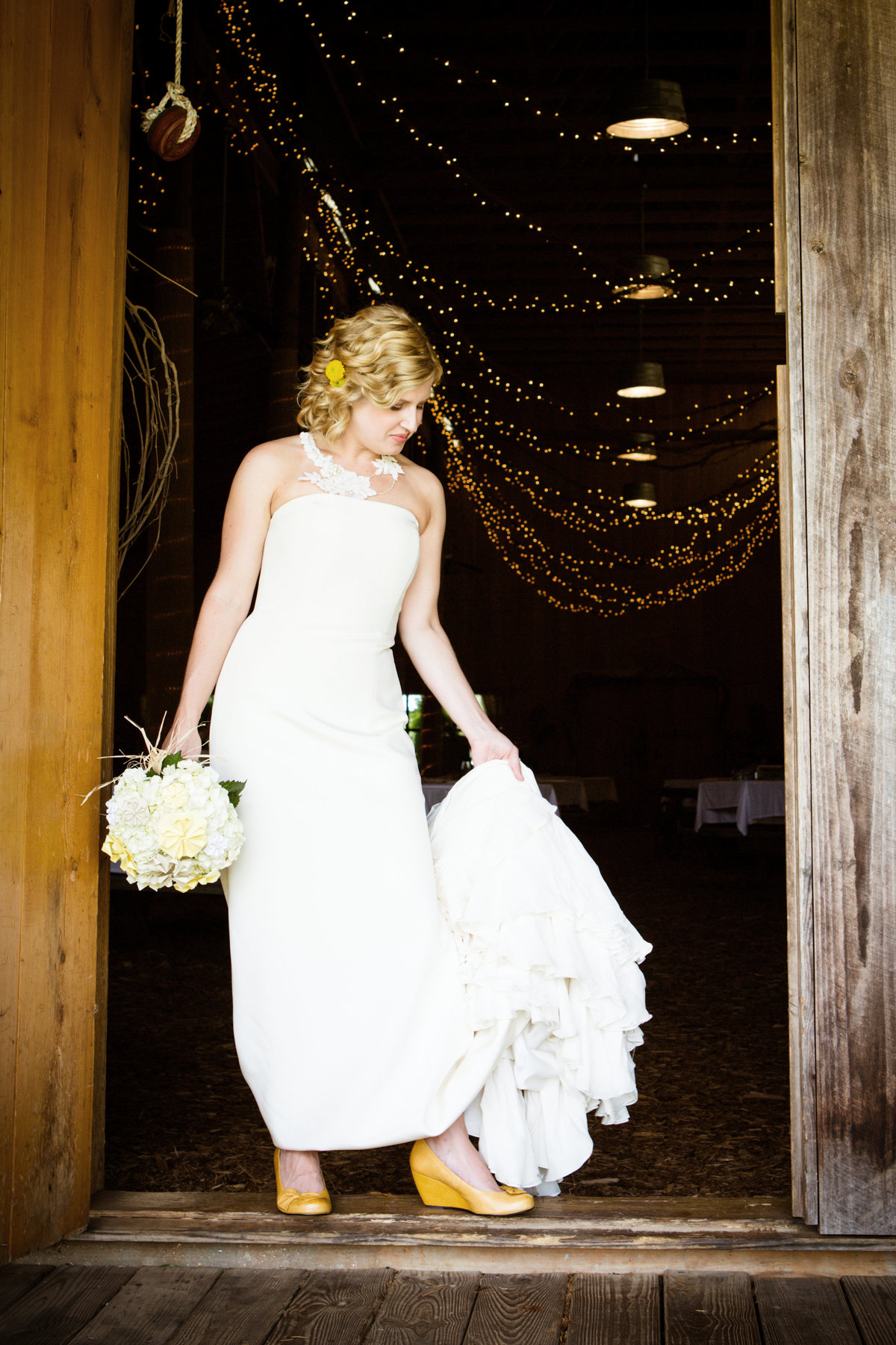A bride poses in the doorway and looks at her shoes at Oak Hollow in Fairhope, Alabama.