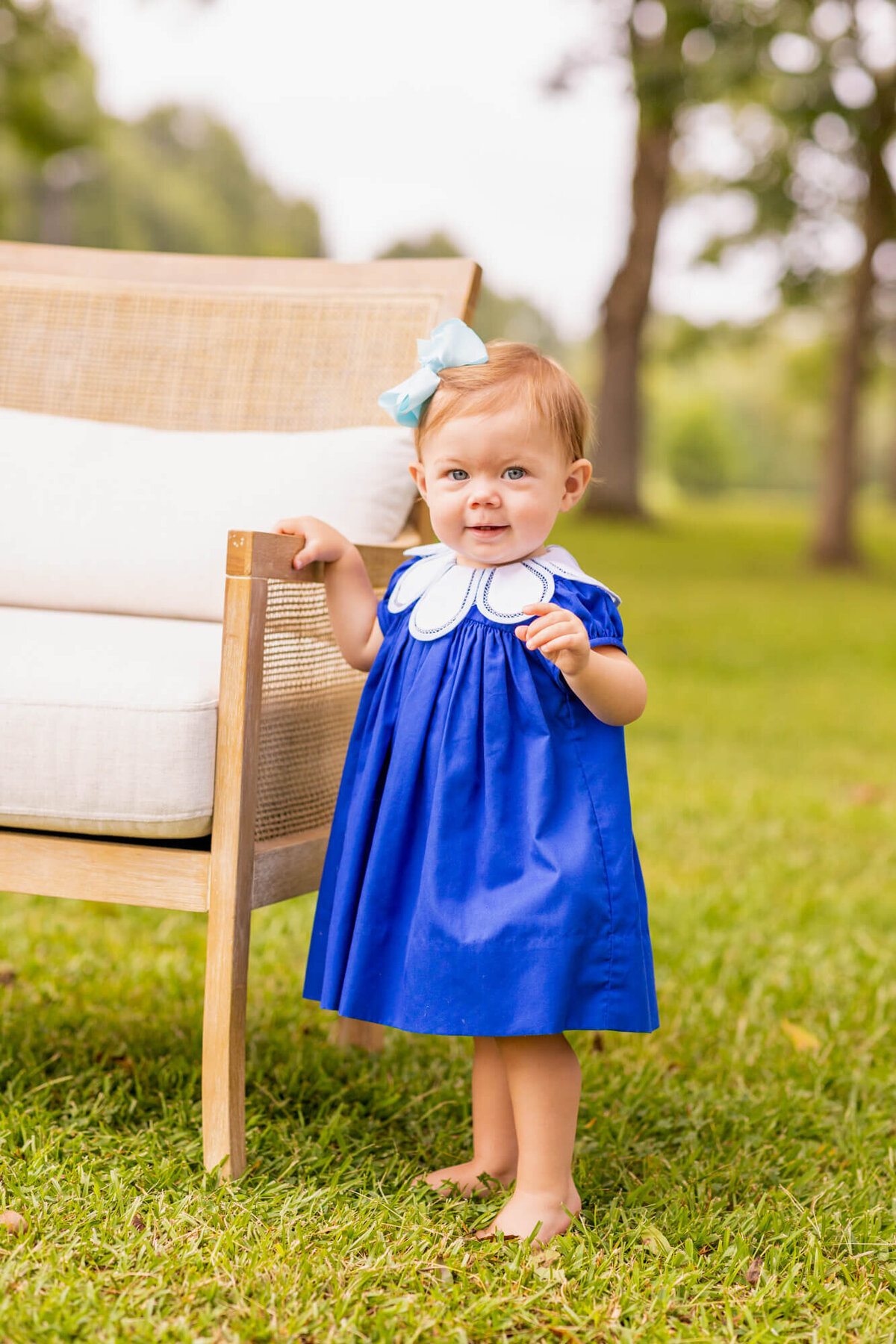 little girl in a cobalt blue dress  standing outside in a field of trees