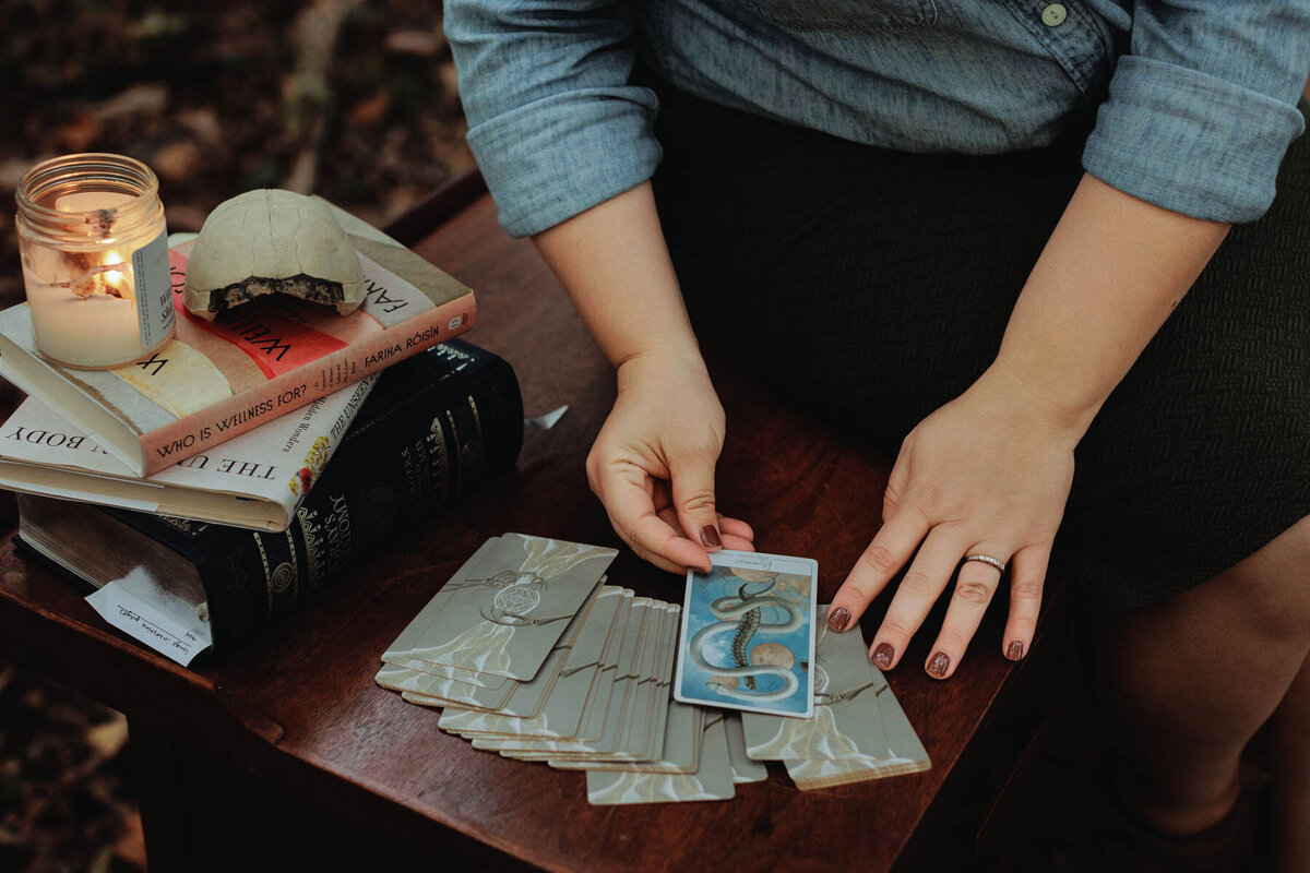 Ash stands over a table where Energy Archaeology Oracle cards are spread out face down and one card has been pulled for a reading