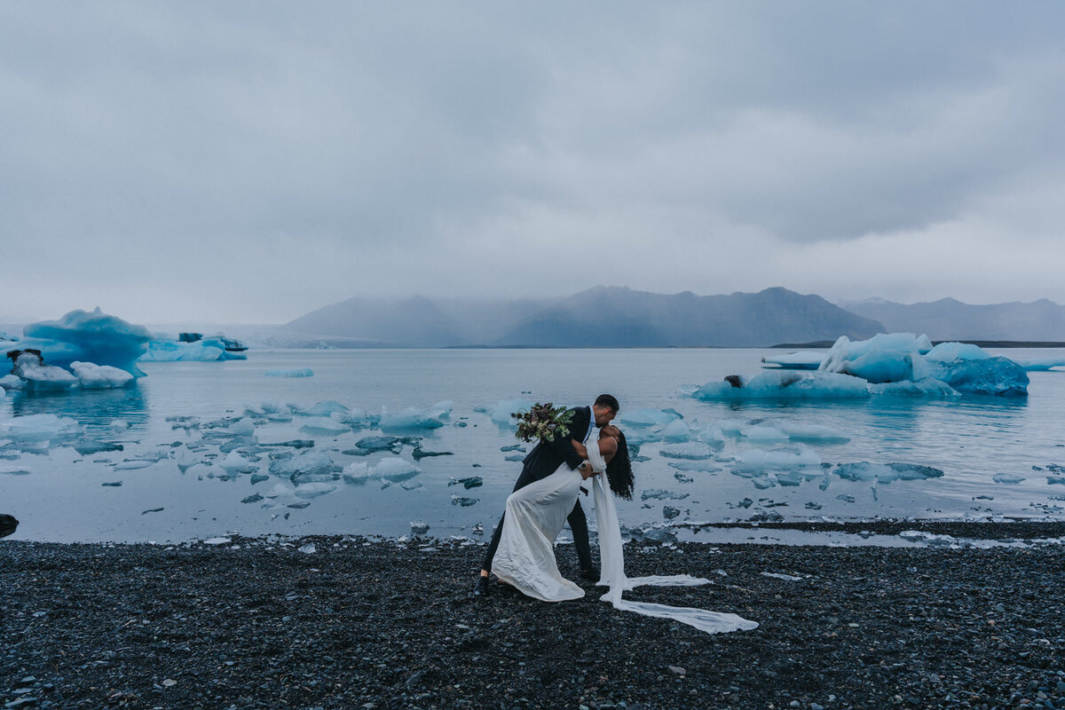 In the heart of Iceland, a couple seals their vows with a kiss in front of a serene glacial lagoon