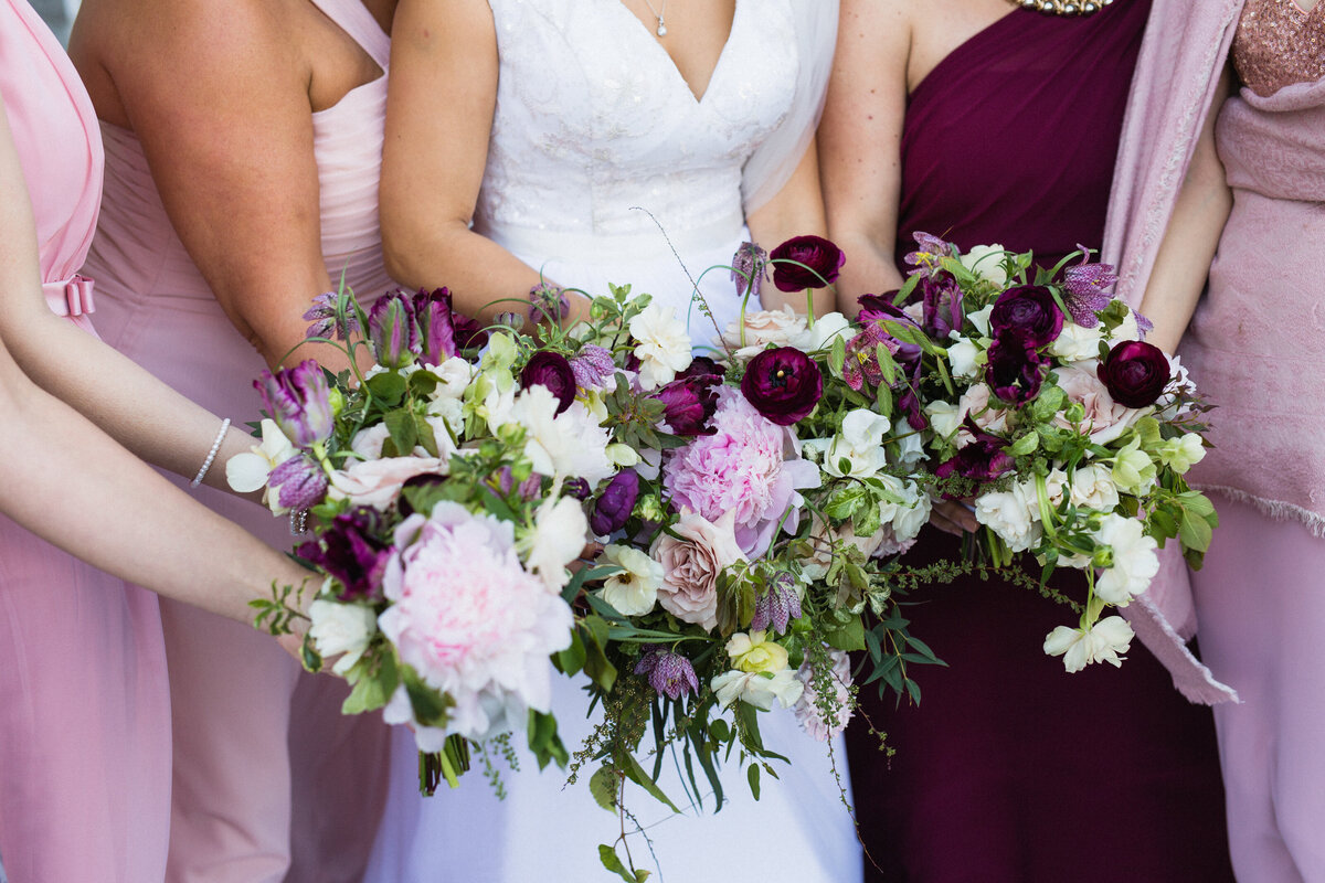 A bride and bridesmaids hold up white and pink garden bouquets at a Montreal wedding.