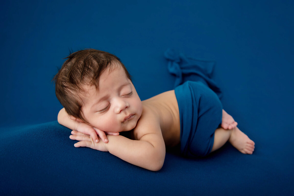 newborn boy side view laying on a blue background for his Burlington, ON newborn photography session