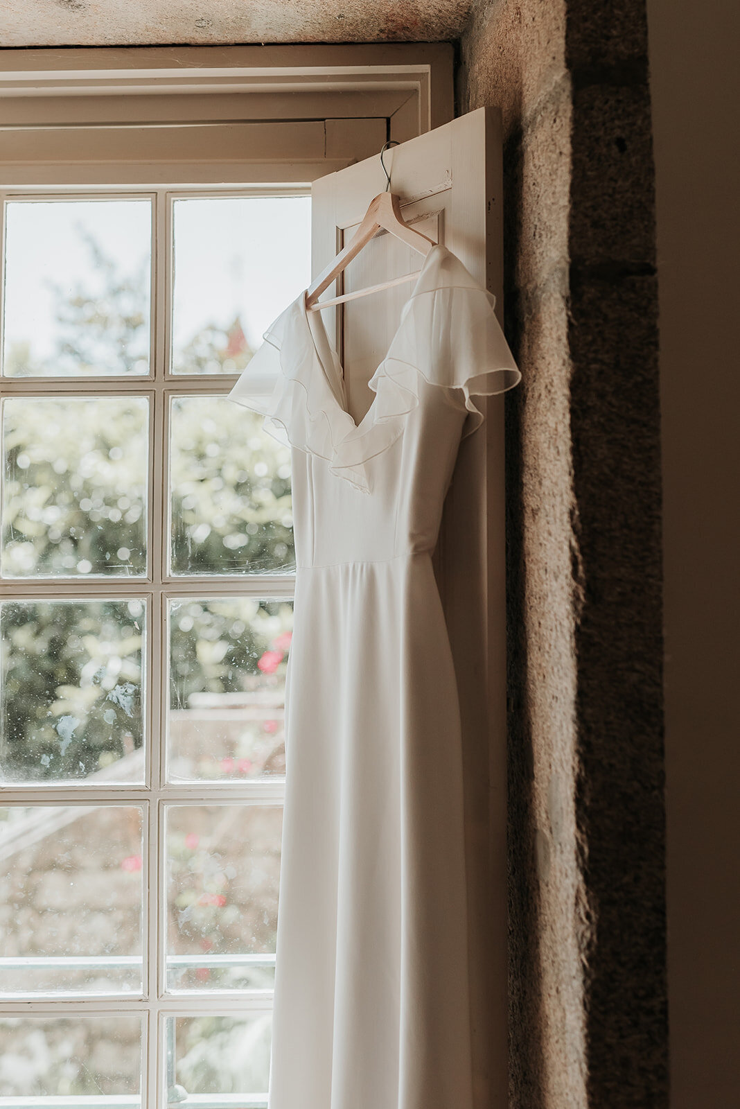Ivory satin wedding dress hanging in window