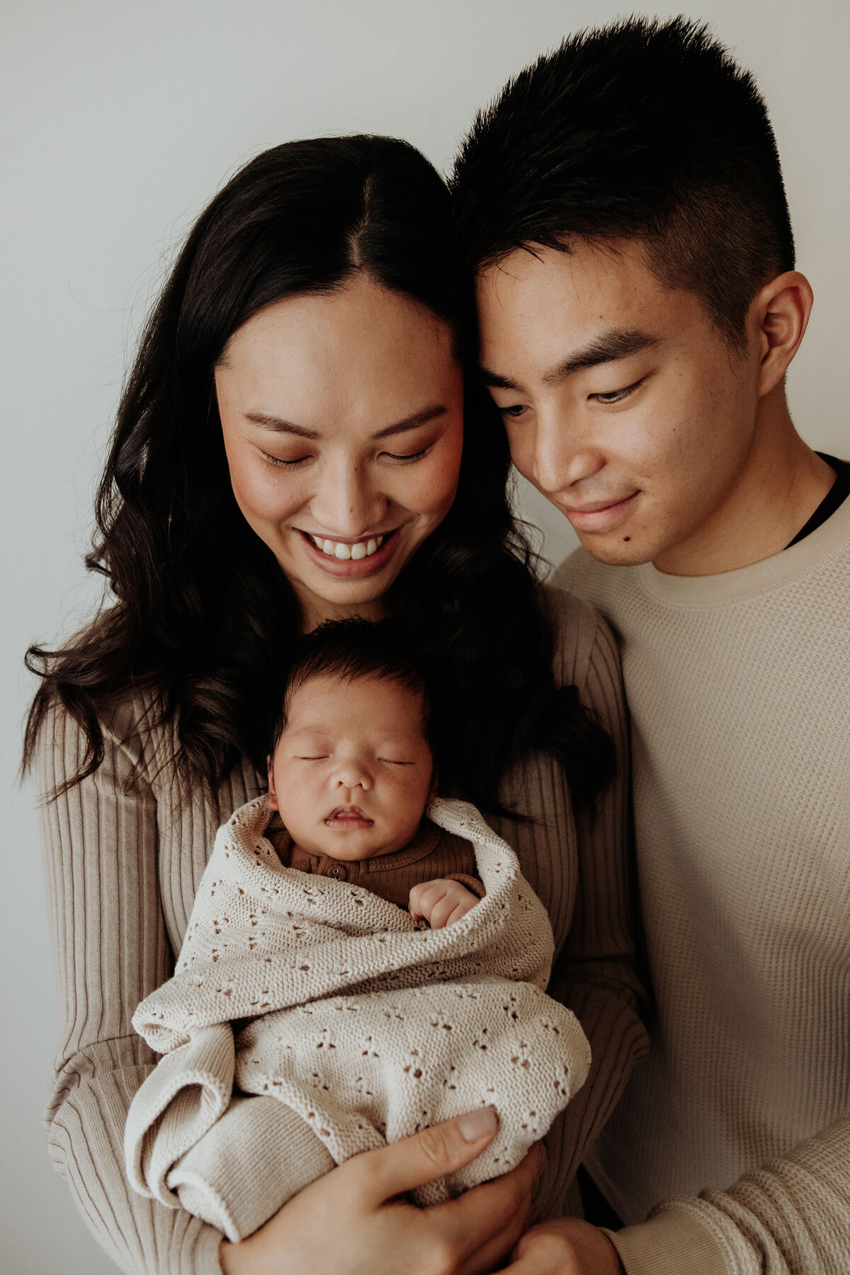Parents cuddle into newborn baby