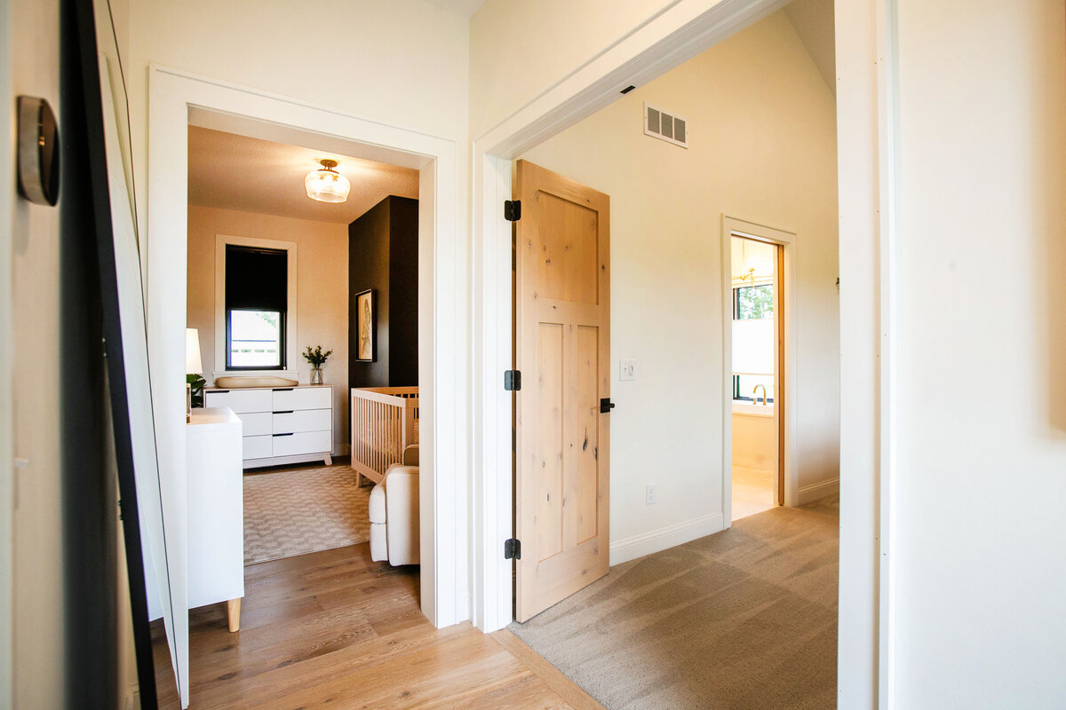 Custom nursery nook in Otsego home with dark walls, wood floors and modern accents designed by Cornerstone Custom Builds