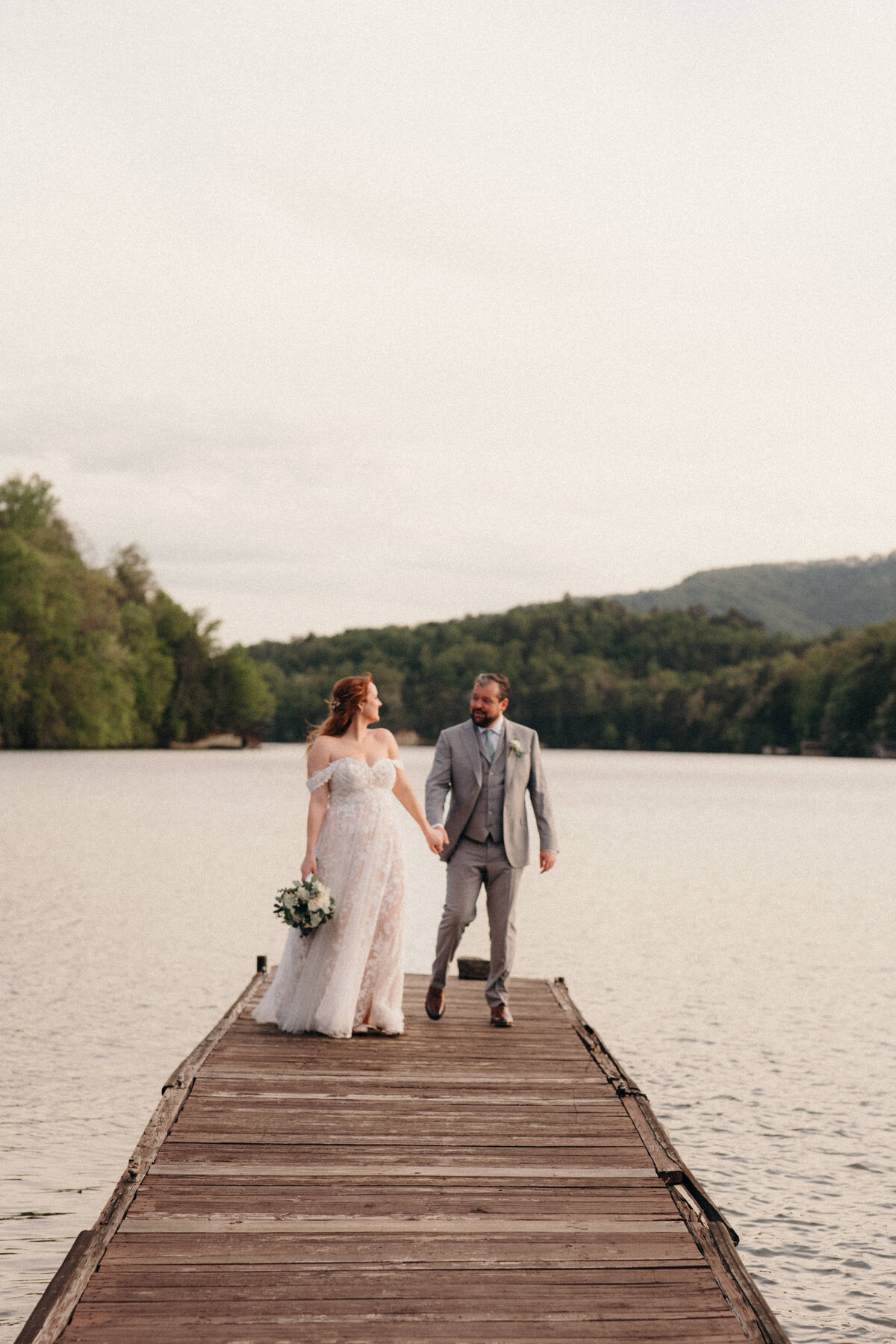 A bride and groom on a dock with water around them in Lake lure, NC.
