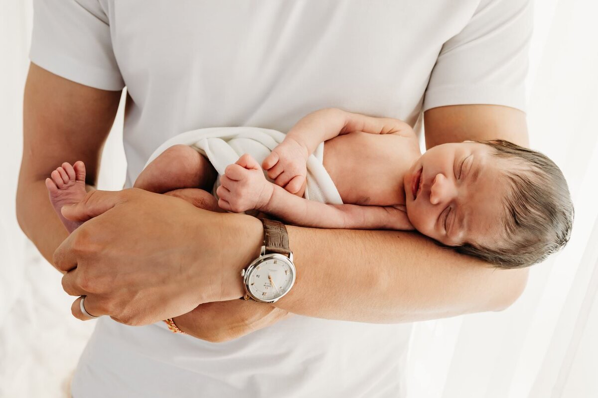 baby sleeping in dads arms