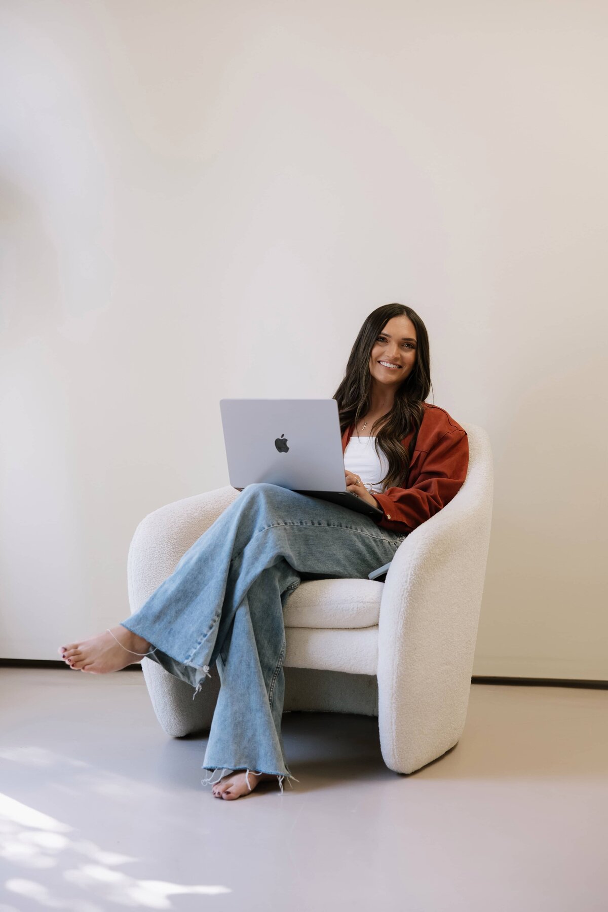 A health coach sits on a chair with her laptop during her personal branding session. 