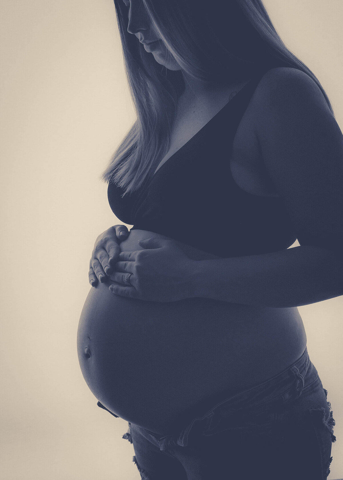 Details of a pregnancy bump in a bra and open jeans in black and white