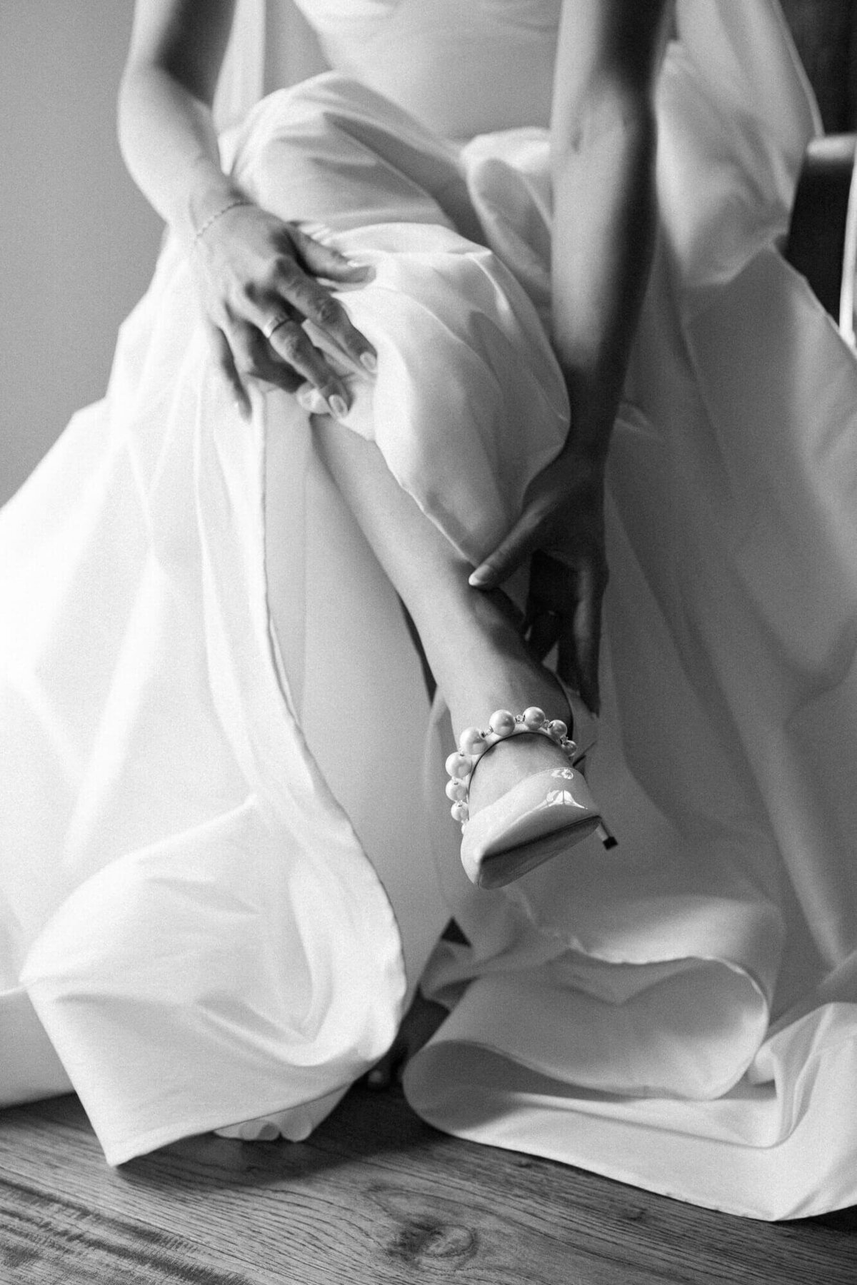 Black and white detail of bride adjusting her pearl heels before the ceremony, captured by a luxury wedding photographer in Scottsdale.