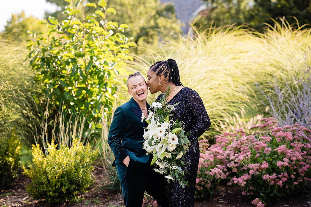 Joyful couple in formal wear sharing an intimate moment, surrounded by ornamental grasses and bright flowers