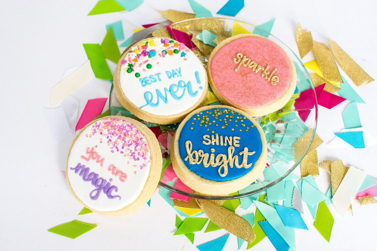 Four decorated sugar cookies  with encouraging phrases like "Best day ever!" written on top