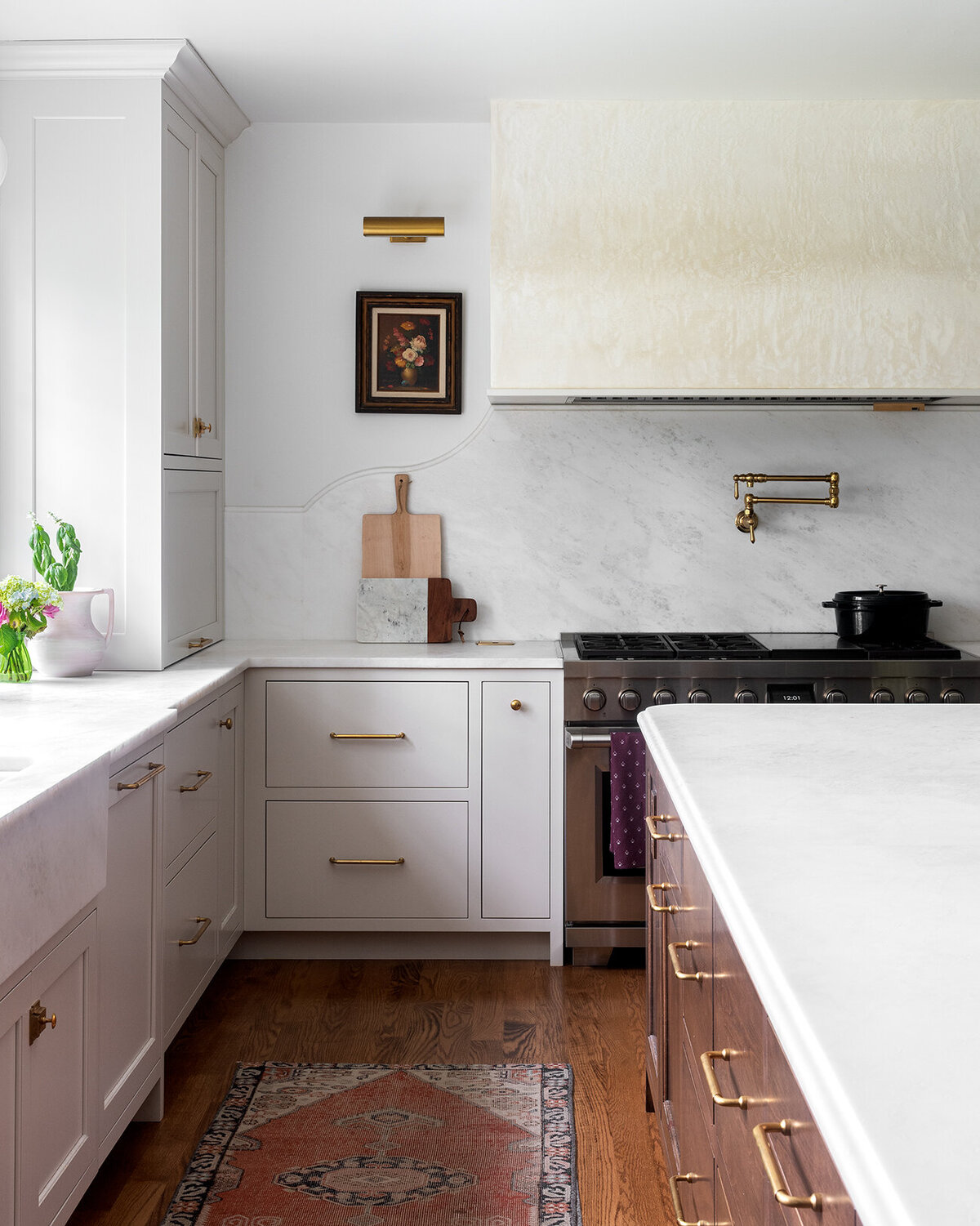 bright white kitchen with gold accent and stainless stove top and range hood
