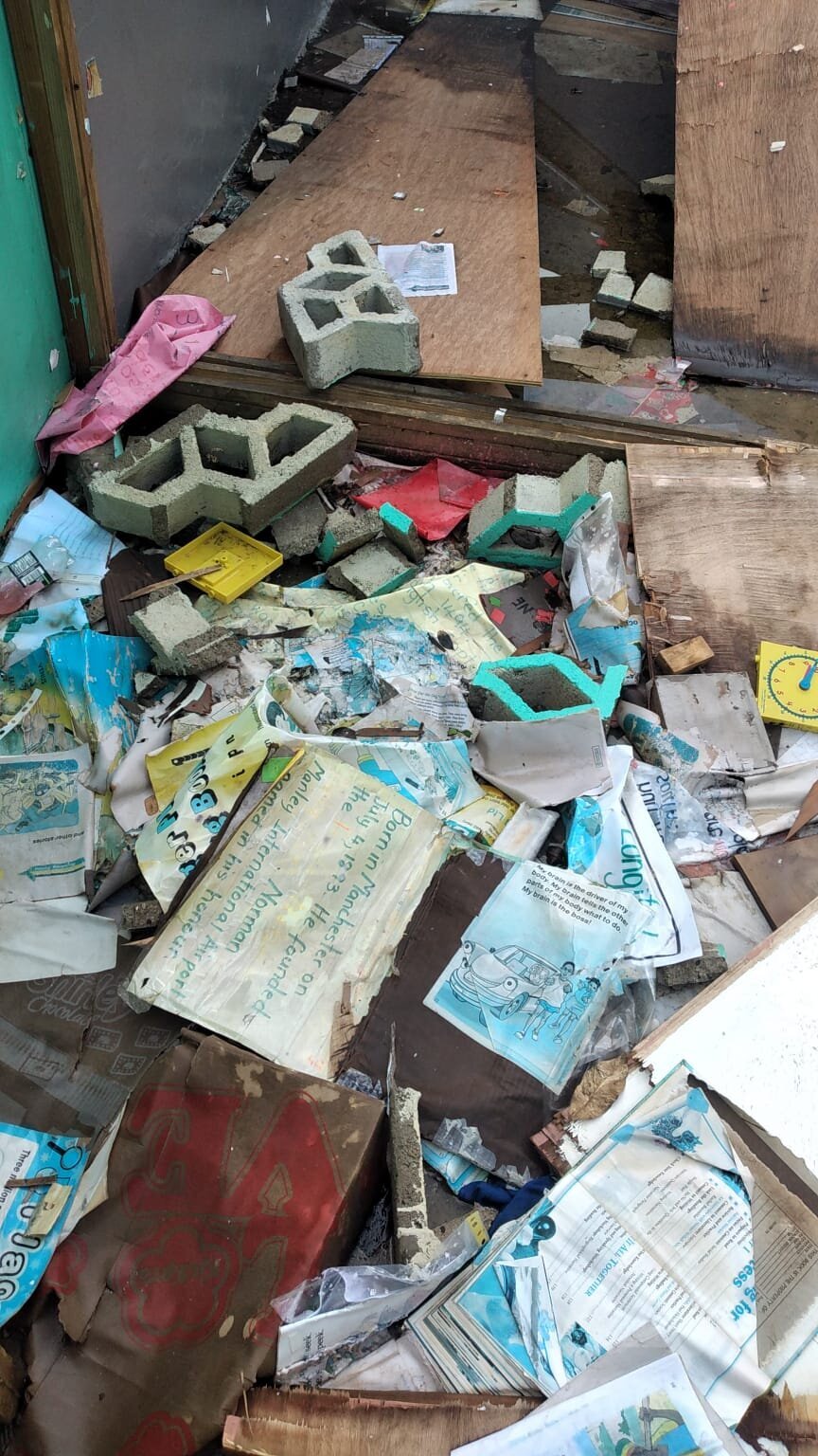 Soaked schoolbooks and destroyed learning materials scattered across the floor.