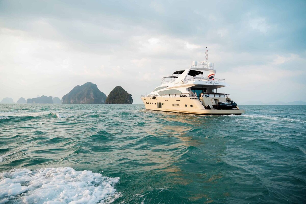Luxury motor yacht with sleek white sails gliding across crystal-clear waters of the Andaman Sea.