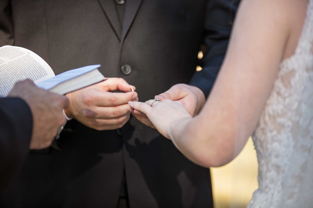 groom places ring on brides finger at wedding near Austin Texas
