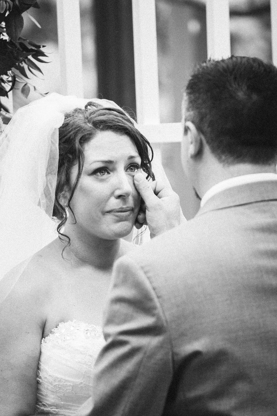 Groom wiping tear from bride