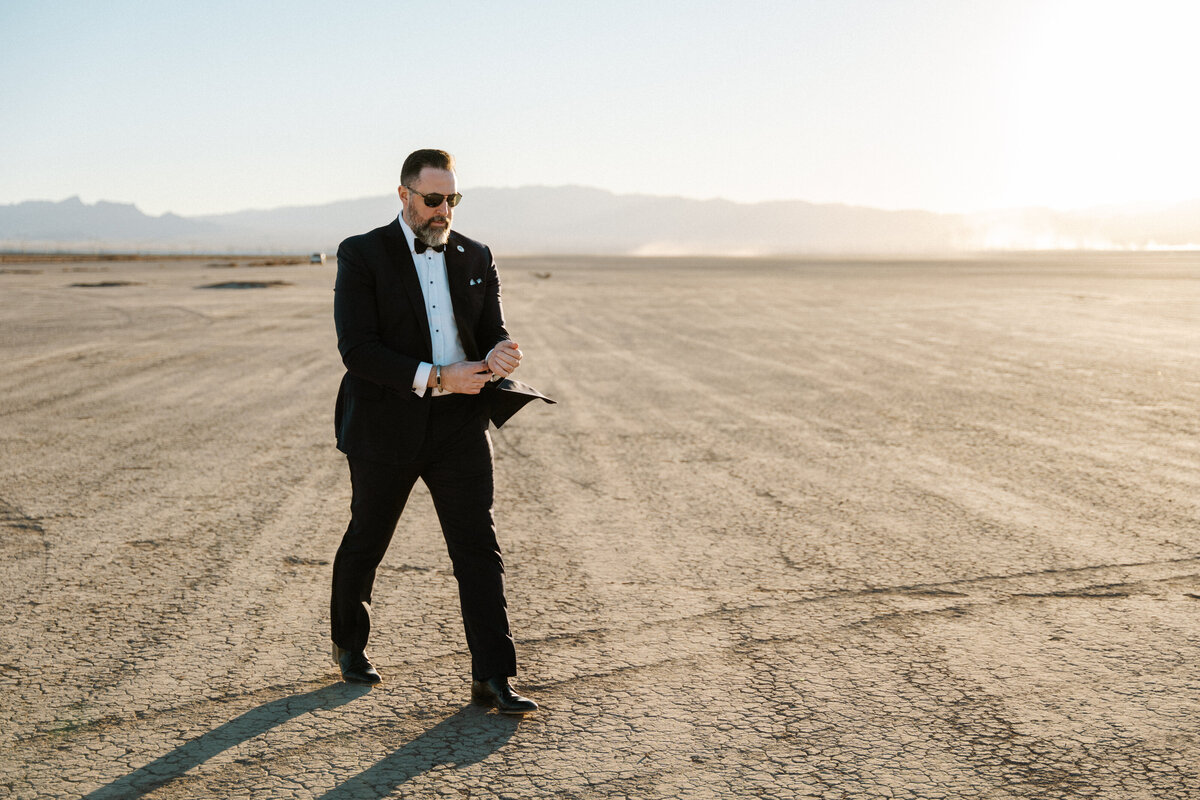 groom walking through the boulder city dry lake bed at golden hour