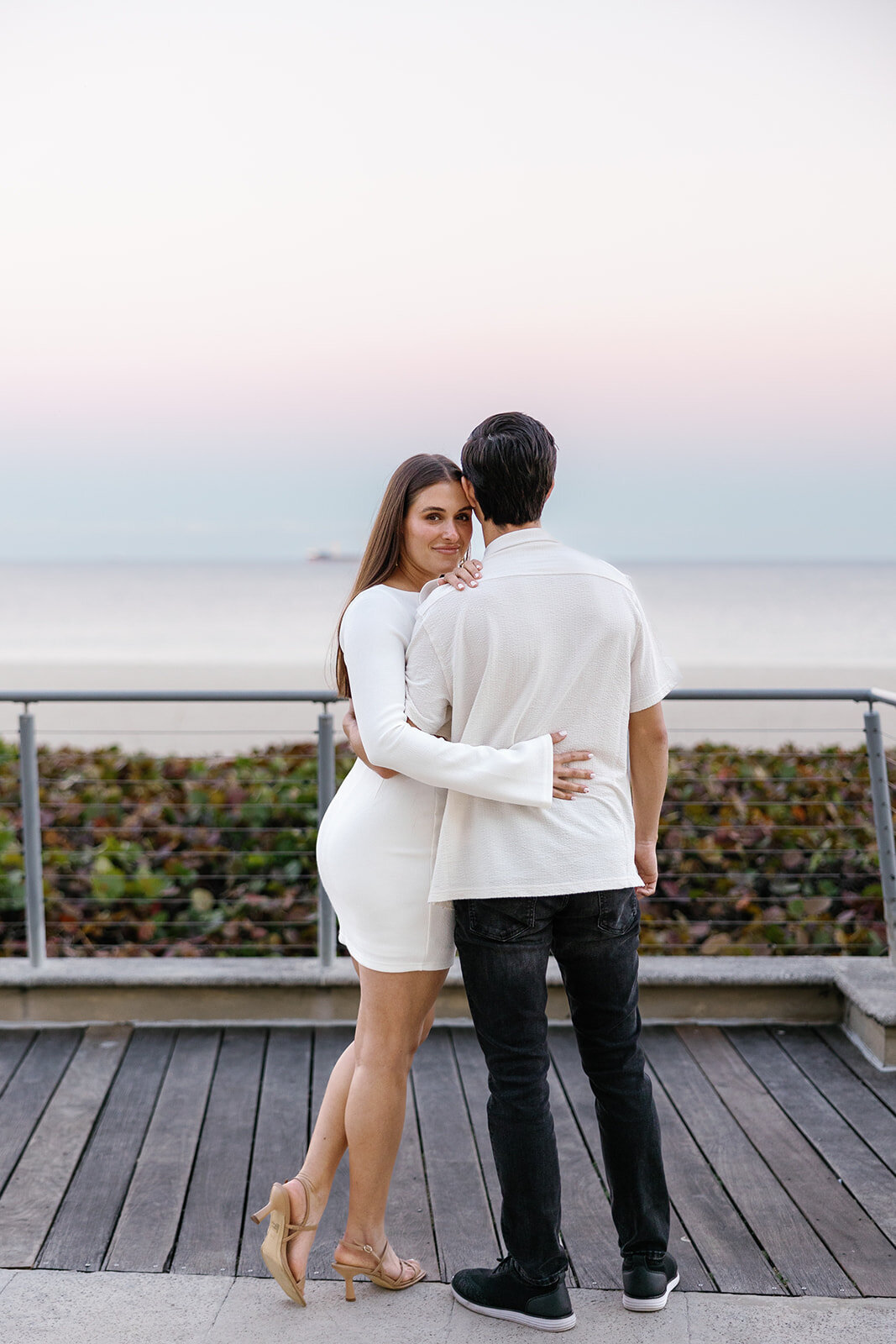 Rebecca and Graysen hold each other closely on the green lawn of Marriott Hotel Fort Lauderdale, sharing a romantic moment from their Claudia Amalia Engagement Photography session.