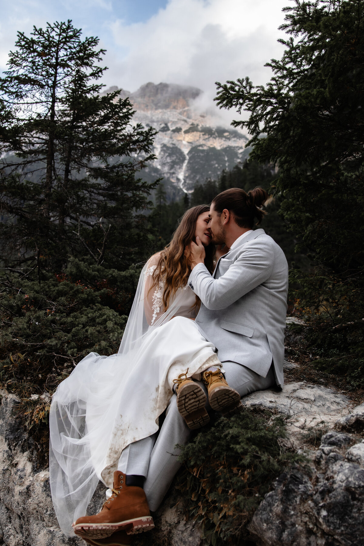Elopement wedding couple posing on a cliffside with dramatic mountain views