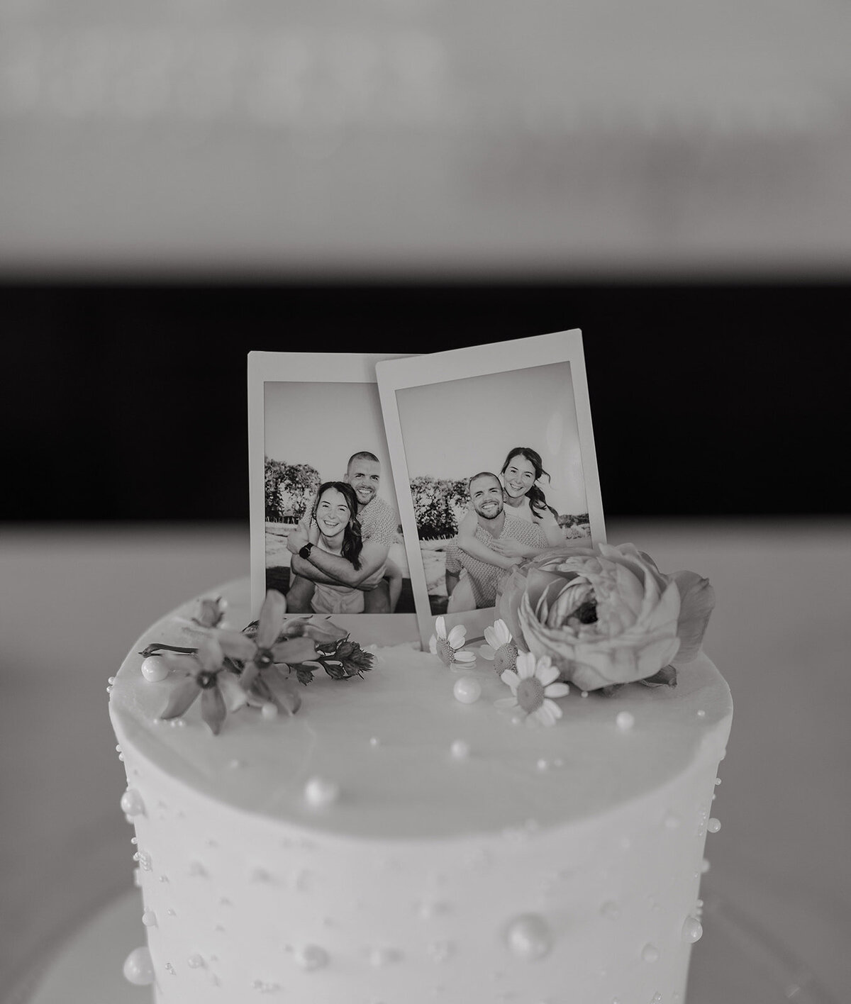 A wedding cake with two polaroids on it