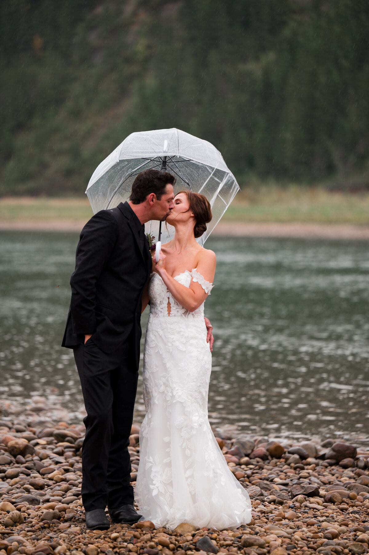 wedding couple kiss under umbrella during rainy day wedding