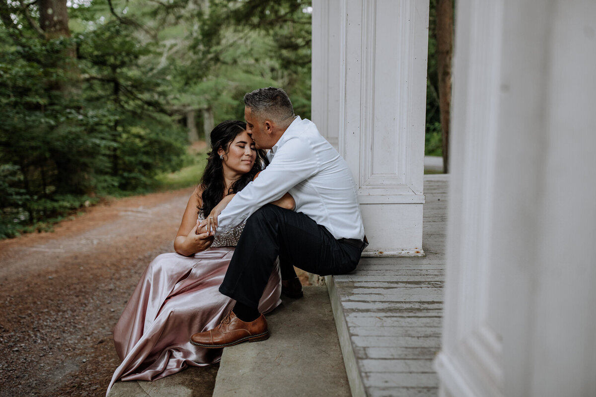 Bride and groom holding hands looking at each other while standing in front of rolling hills with the sunlight coming down on them