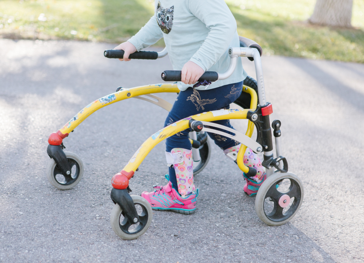 Child learning to walk with Pediatric Gait Trainer, a device that provides support to enable walking and standing.