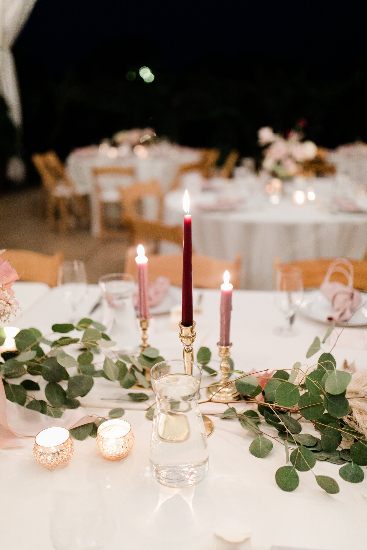 head table decorated with candle sticks and eucalyptus