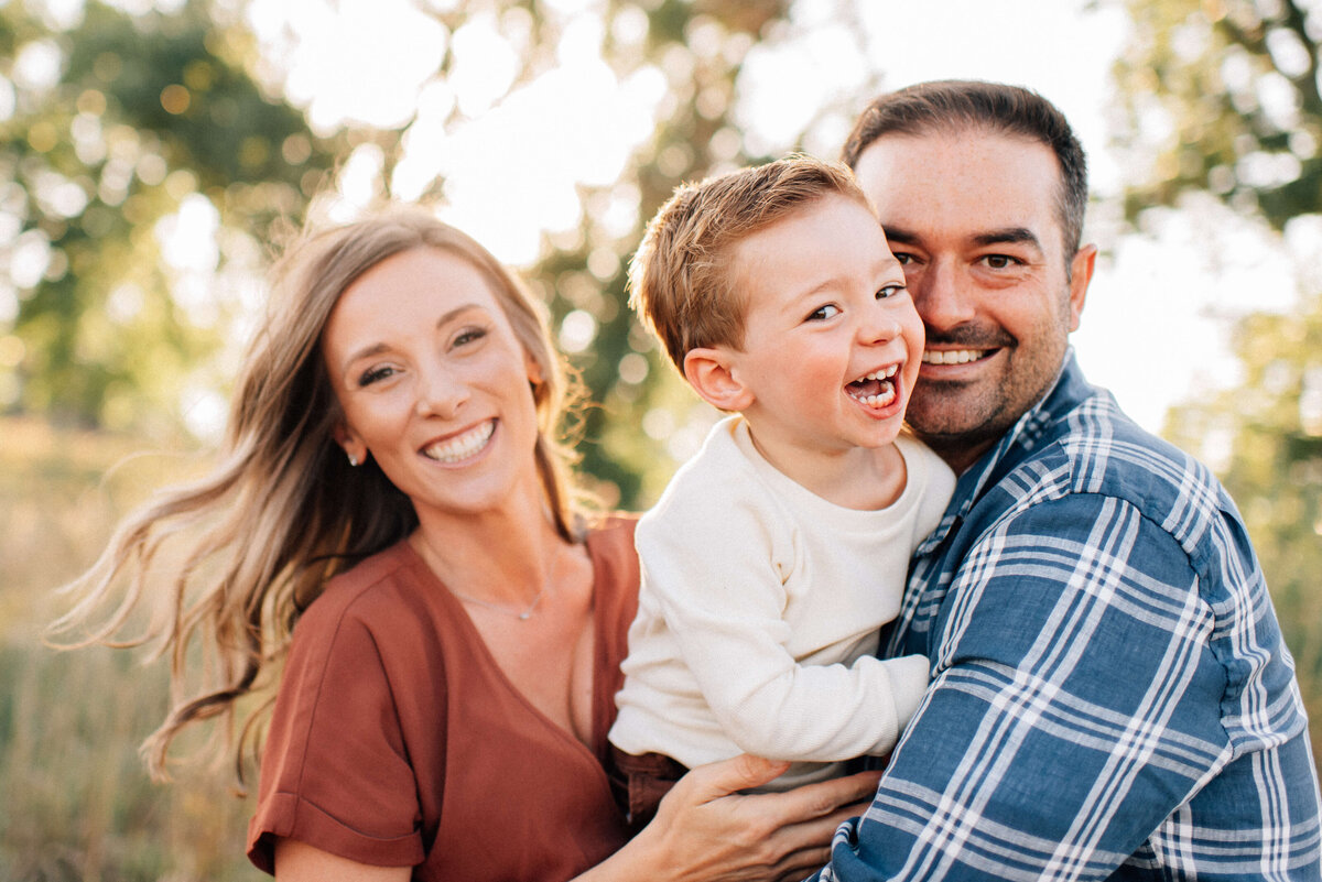 mom and dad holding toddler son and being playful for the photographer
