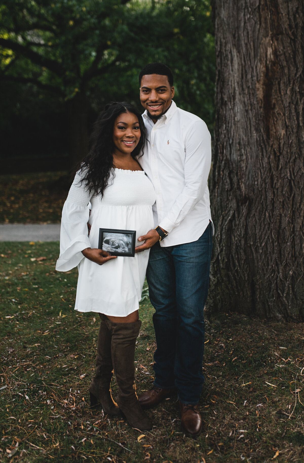 Maternity shot with soon to be mom, and dad kissing holding ultra sound photo.