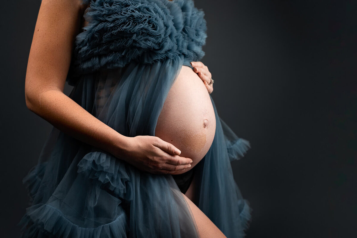 Pregnant belly in a blue gown.