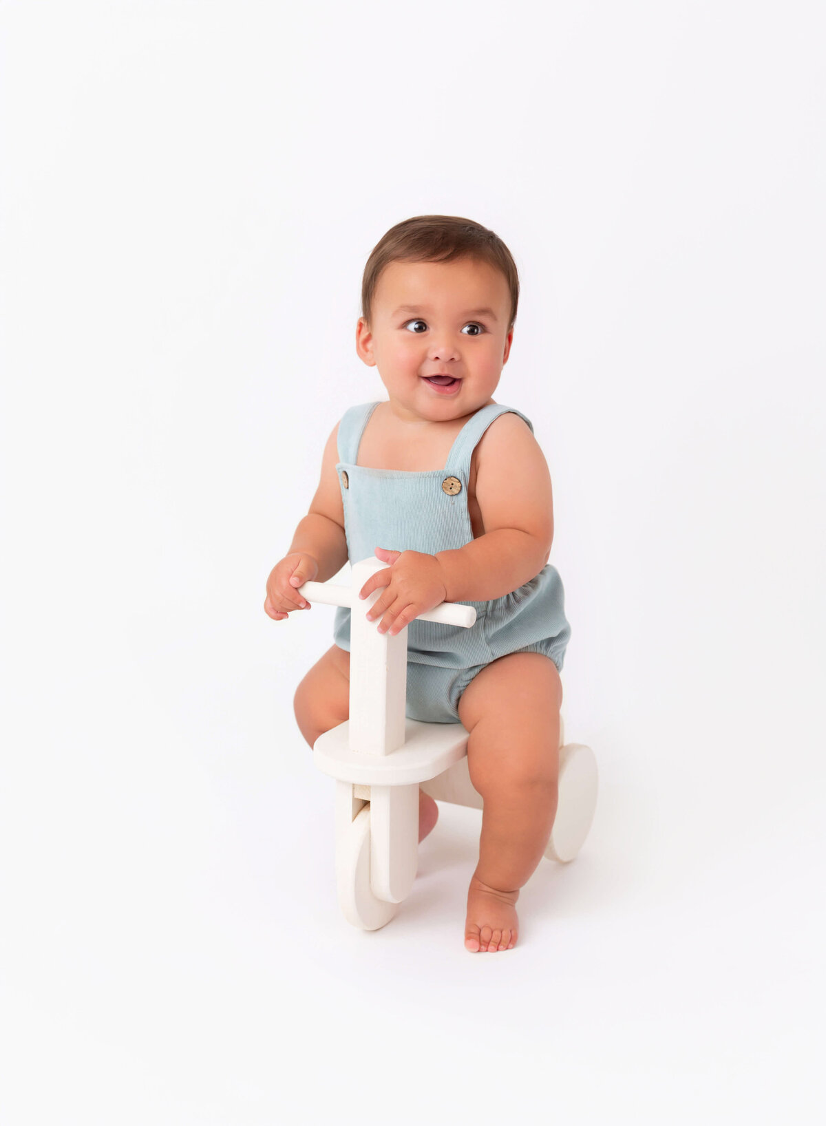 Modern baby photography in NYC baby boy in blue riding a scooter