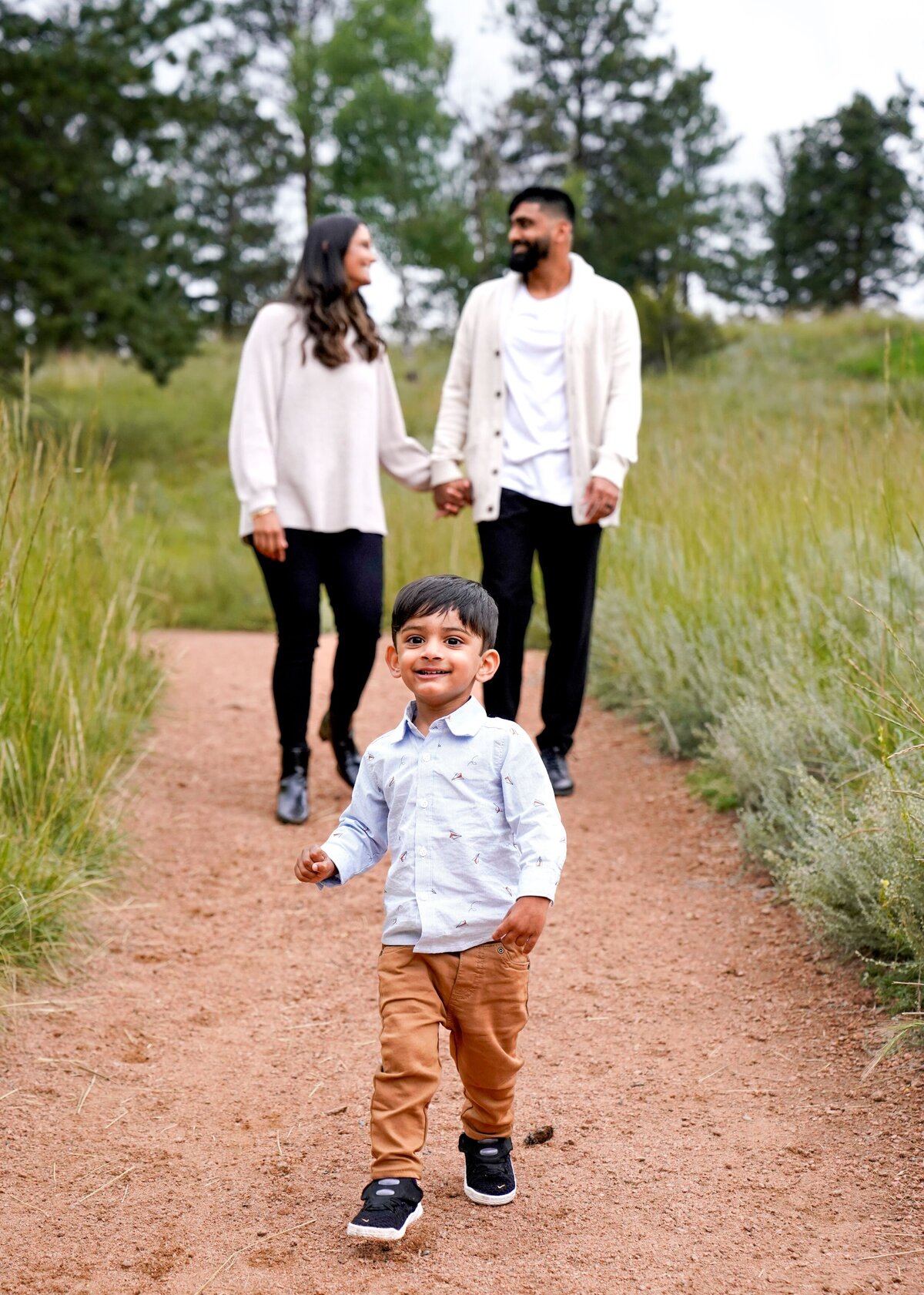 parents holding hands behind small child