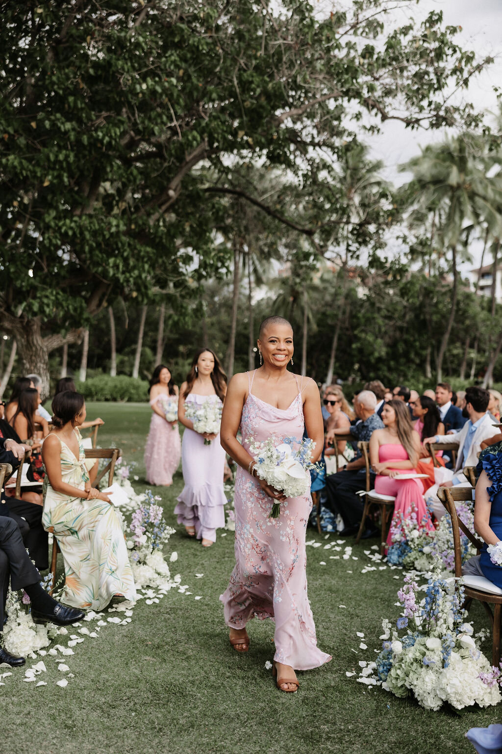 bridesmaids walking down winding aisle at lanikuhonua wearing purple dresses