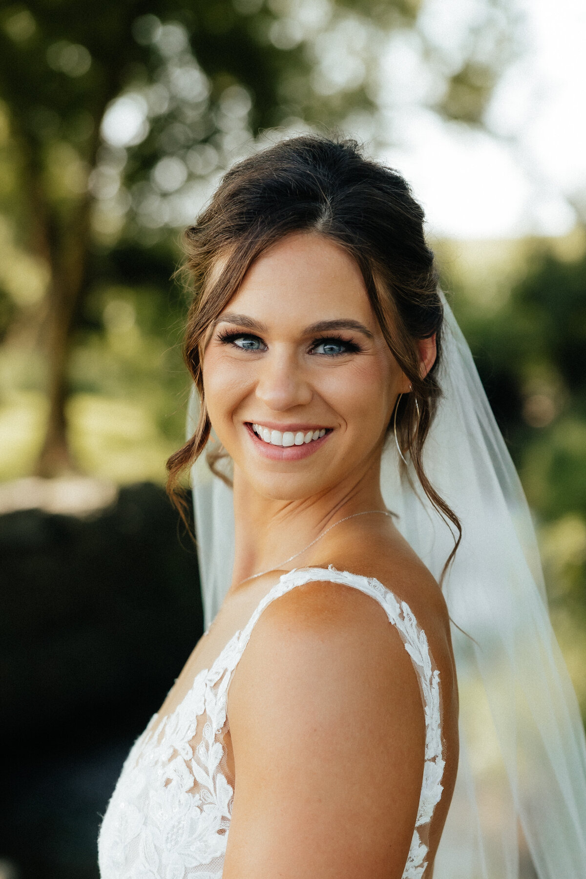 Smiling bride with sleek updo and soft glam makeup in Chicago, IL. Wedding beauty services.