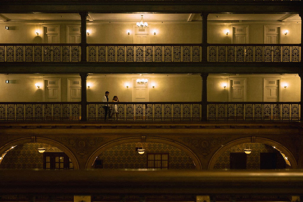 A couple standing on an indoor hotel balcony.