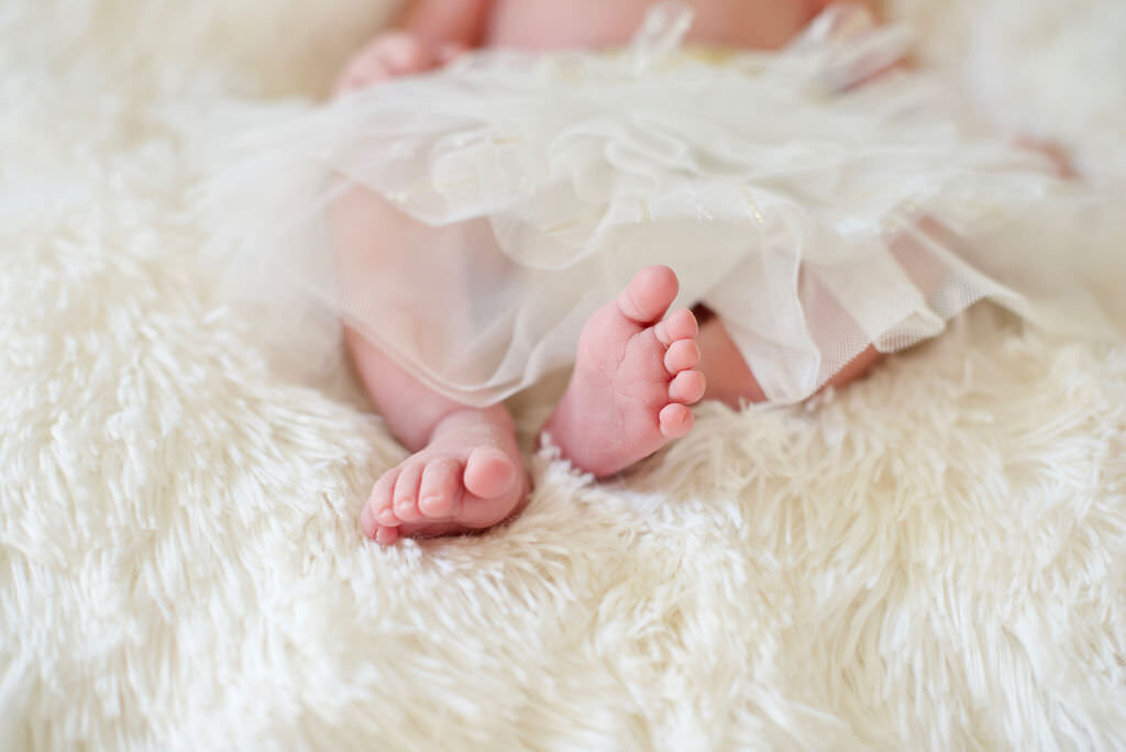 Baby's feet resting on a white blanket.