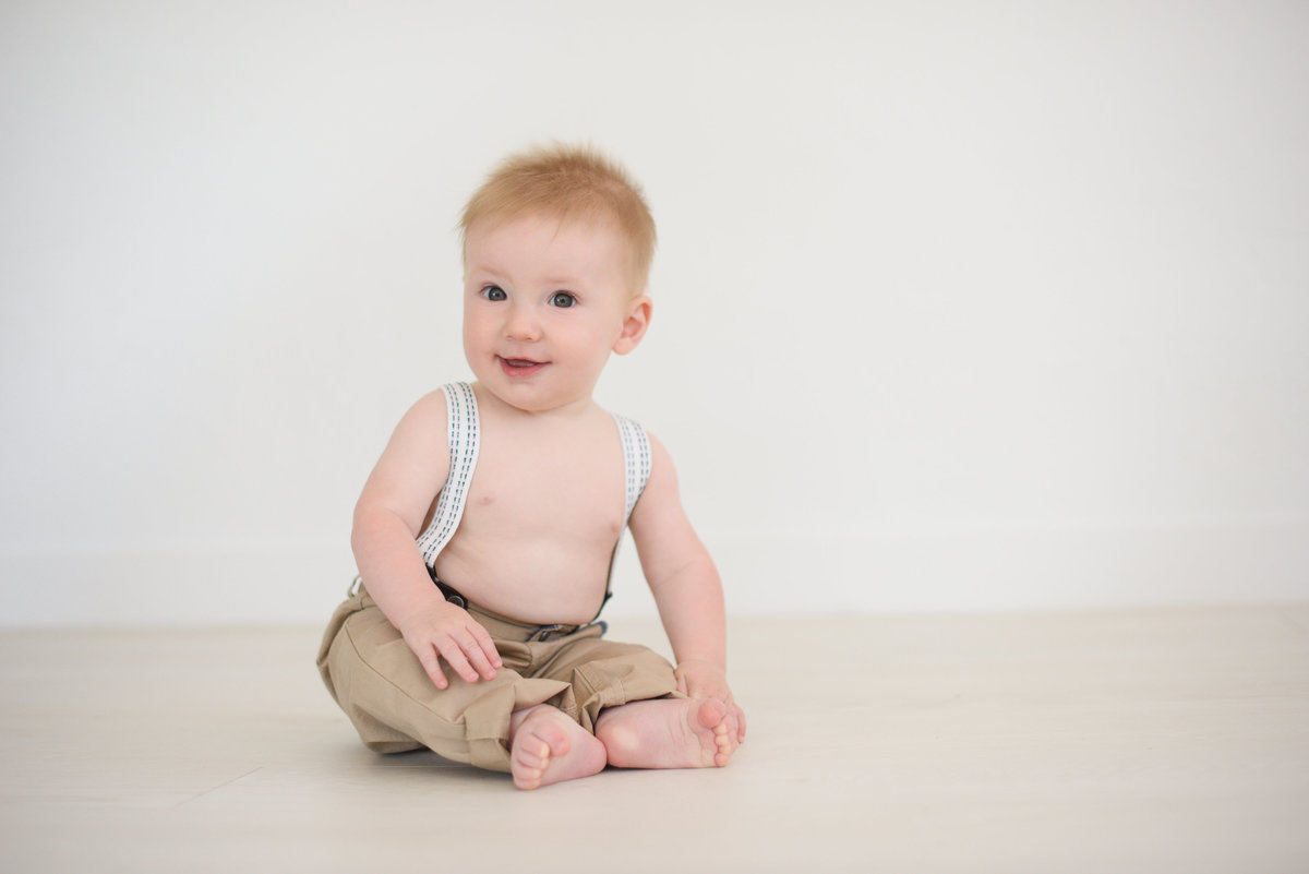 Baby sitting and smiling in portrait studio in Boise.