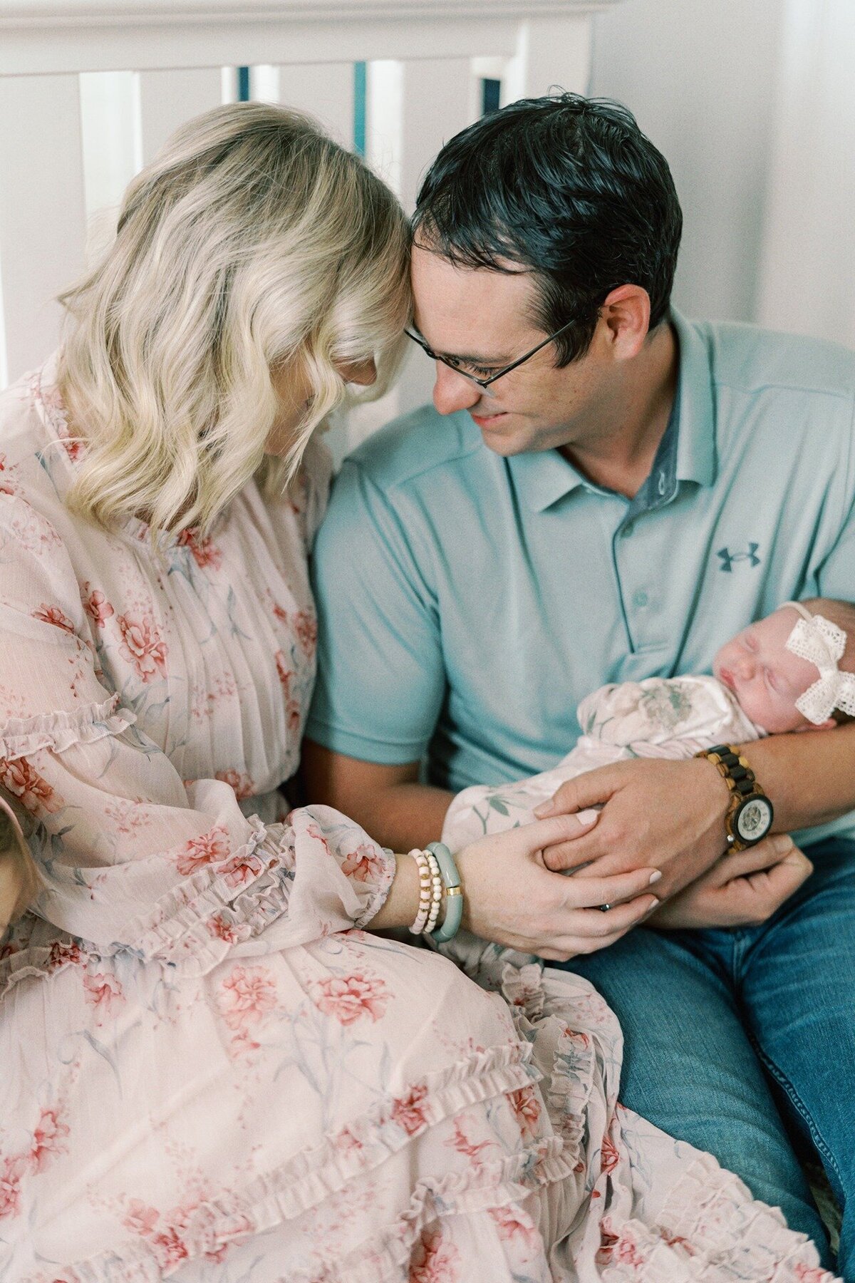 mom-and-dad-with-foreheads-together-while-holding-newborn