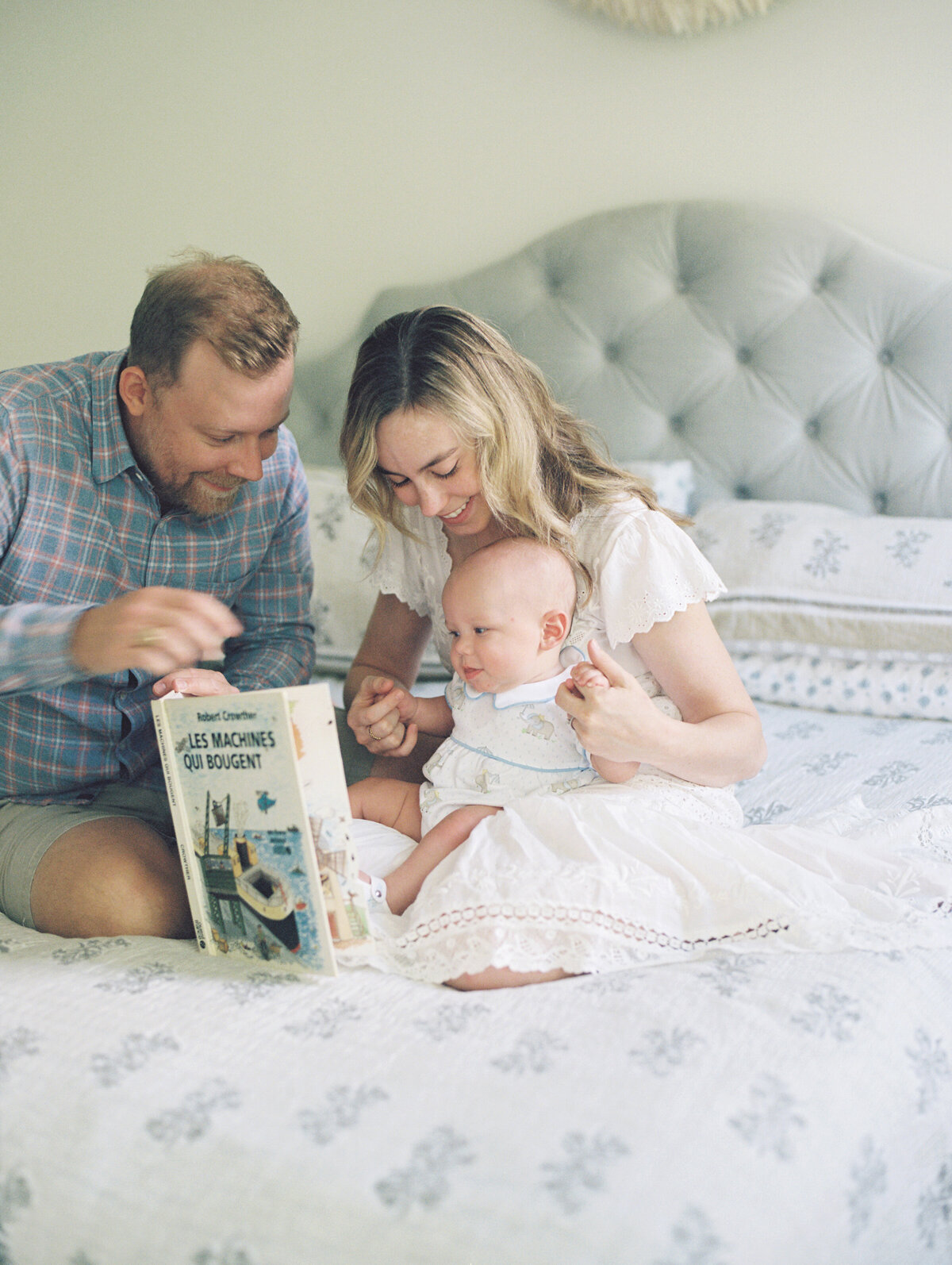 parents with newborn on bed reading book